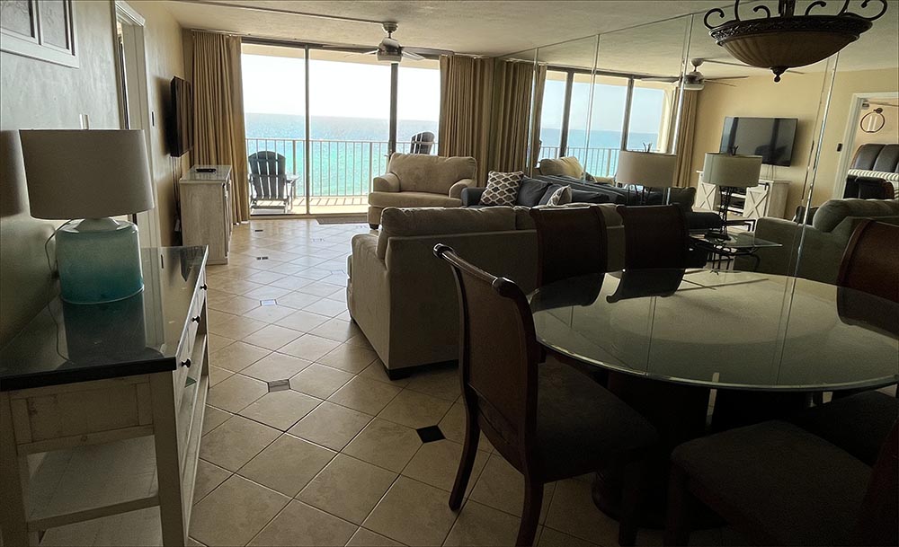 Sunny living room with large flatscreen TV and casual furnishings facing the beach and Gulf of Mexico. 