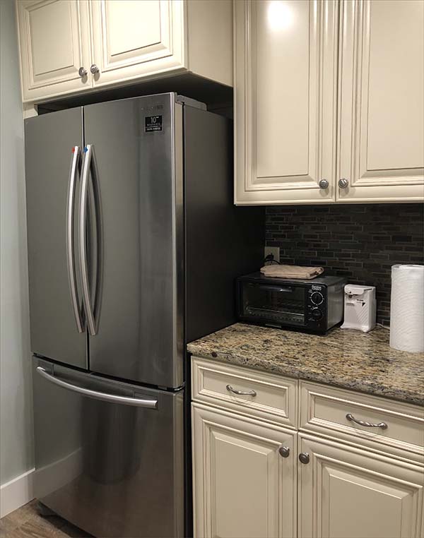 Beautifully appointed kitchen with side by side stainless steel refrigerator and full sized washer and dryer